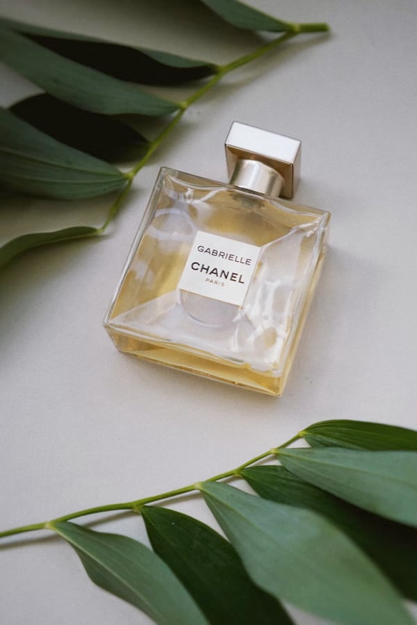 bottle of gabrielle chanel perfume surrounded by a few leaves