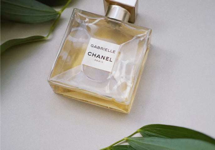 bottle of gabrielle chanel perfume surrounded by a few leaves